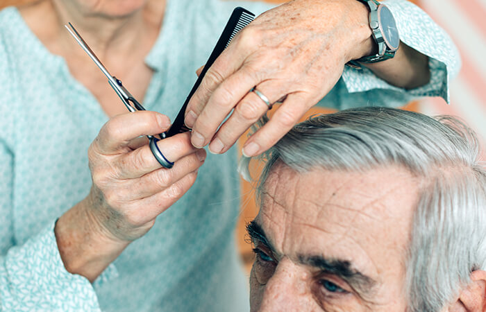 Adulto mayor recibiendo corte de pelo